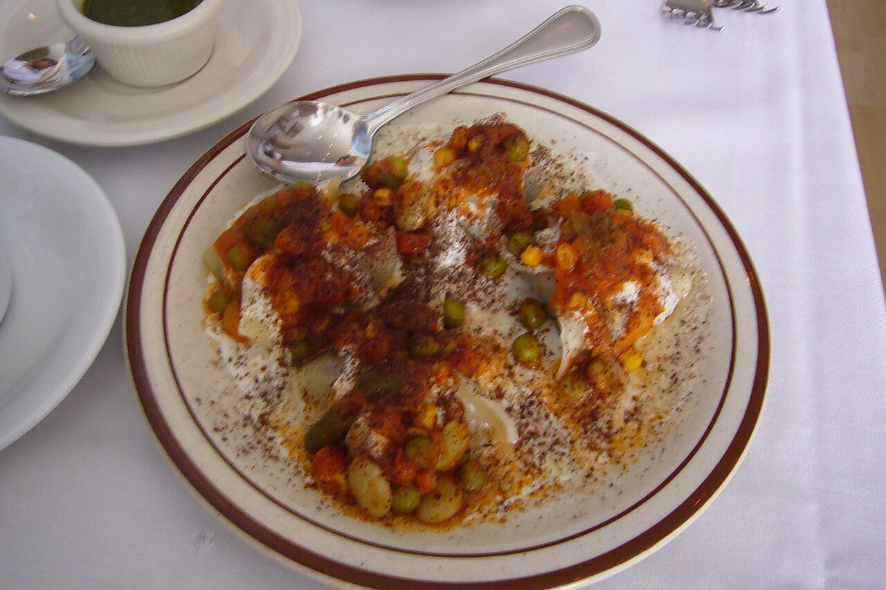 Representative photograph of Afghan Mantu. The photograph includes peas and a red sauce; this draft uses a yellow split-pea topping.