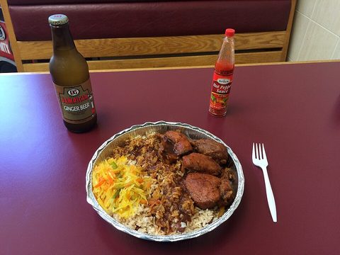Representative photograph of Brown Stew Chicken. The photograph includes rice and fried plantain as side dishes.