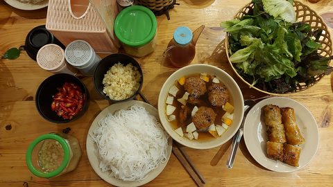 Representative photograph of Bun Cha. The photograph includes spring rolls and extra herbs not included in this draft.