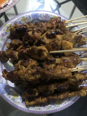 Representative photograph of Chicken Satay with Kecap. The photograph shows chicken skewers coated with peanut sauce.