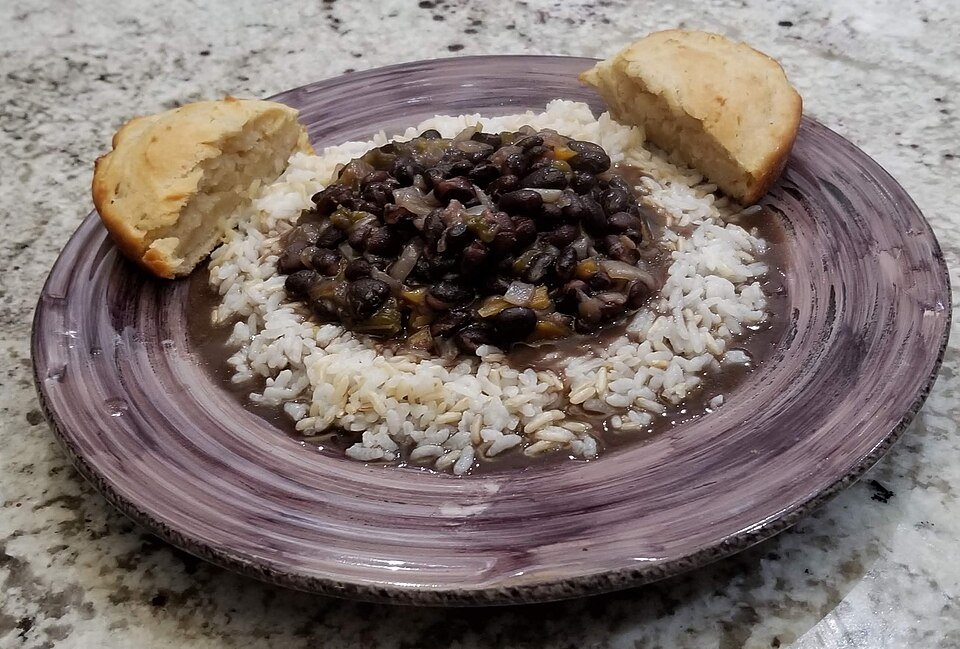 Representative photograph of Cuban Black Beans. The photograph includes rice and bread as accompaniments.