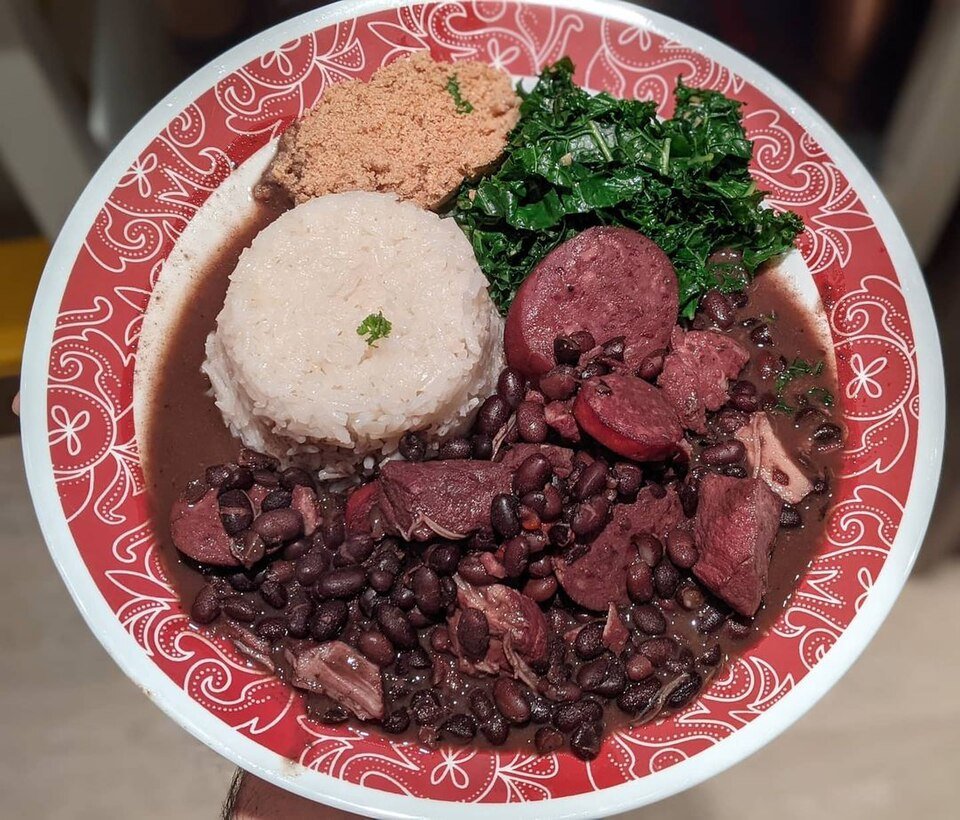 Representative photograph of Feijoada. Rice, greens and cassava flour are shown as accompaniments.