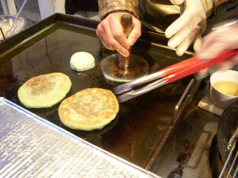 Representative photograph of Hotteok. The photograph shows hotteok cooking on a griddle, rather than a plated serving.