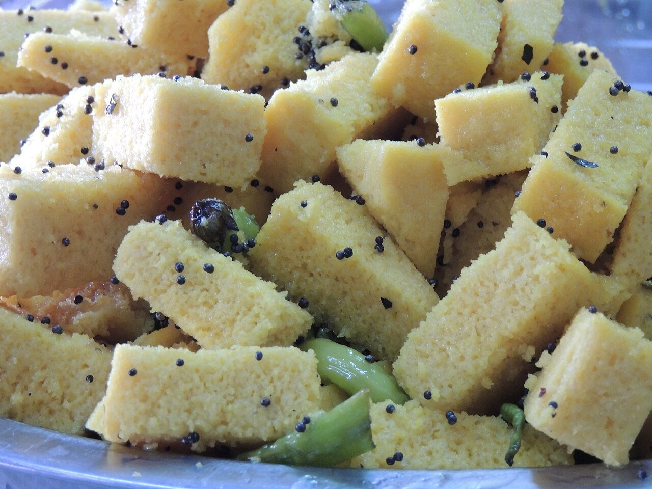 Yellow khaman cubes with mustard seeds and green chilies