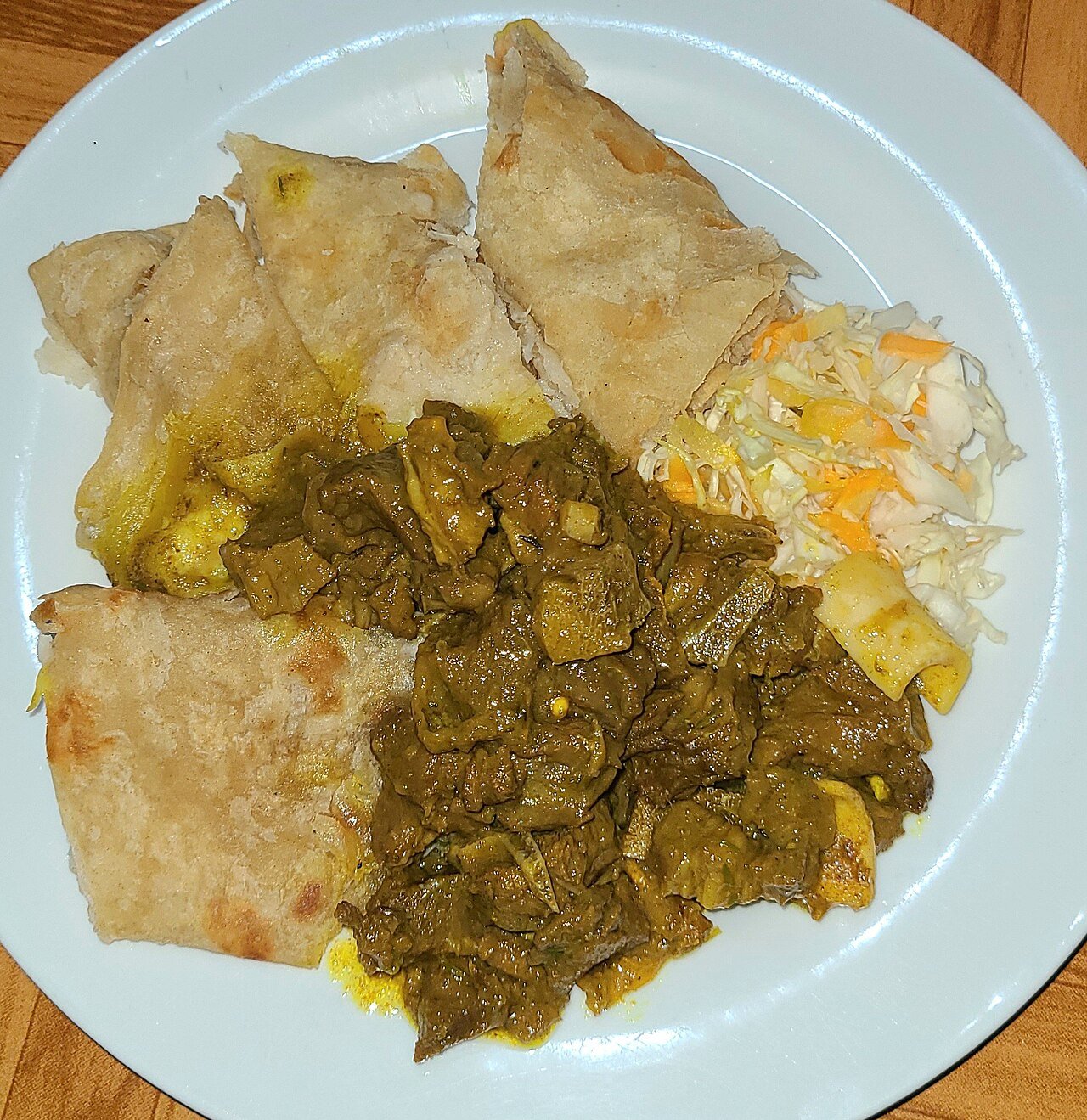 Representative photograph of Jamaican Curry Goat. The photograph includes roti and slaw not included in this draft.