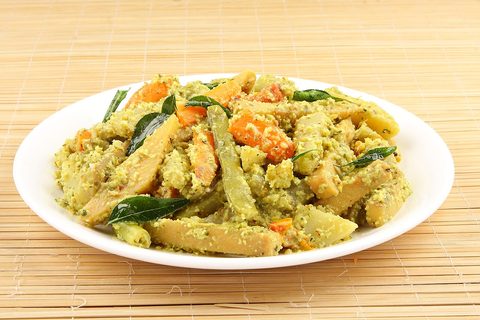 Mixed vegetables coated with coconut and curry leaves on a white plate