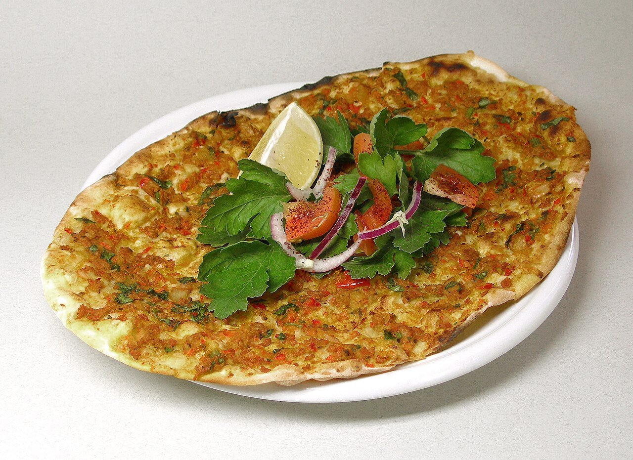 Representative photograph of Lahmacun. The photograph includes lemon and salad garnish not included in this draft.