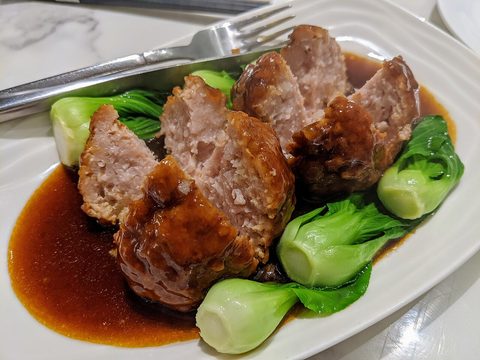 Representative photograph of Lion Head Meatballs. The photograph shows a thicker brown sauce and different greens than the cabbage broth in this draft.