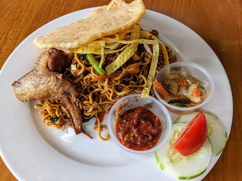 Representative photograph of Mie Goreng. The photograph includes crackers, pickles and a chicken wing; this recipe uses chicken strips.