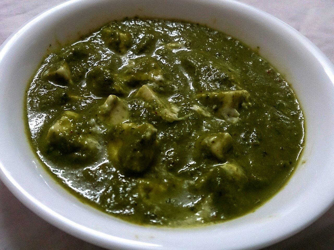 Paneer pieces in a dark green spinach gravy