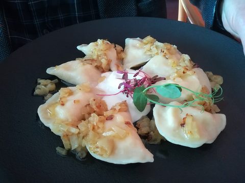 Representative photograph of Pierogi Ruskie. The photograph includes onion and other garnish on top; this draft serves the dumplings with butter.