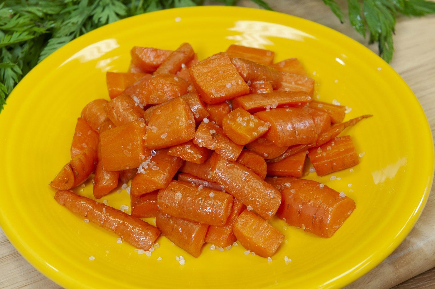 Photograph of roasted carrot pieces with salt on a yellow plate
