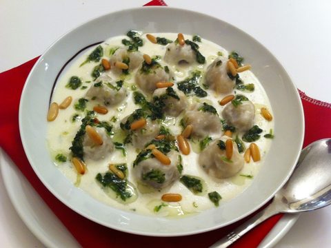 Representative photograph of Shish Barak. The photograph includes a herb and nut garnish.